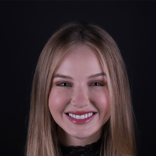 Imagem da paciente Kelin Uess sorrindo enquanto exibe seus dentes recém tratados com resina composta.